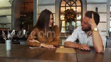 不错的一对夫妇<strong>坐在餐馆</strong>里。 她正喝着茶，看着菜单，而她的男朋友却在